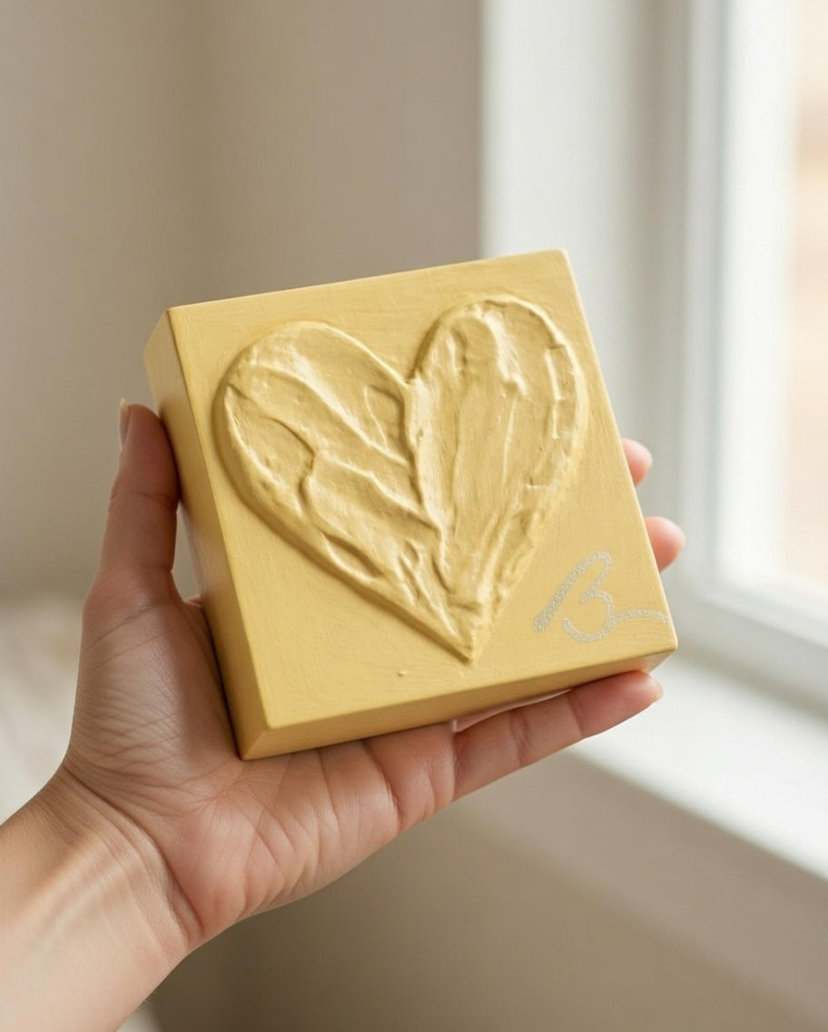 Balanced Ochre heart sculpture in lifestyle setting — soft butter yellow with textured brushstrokes